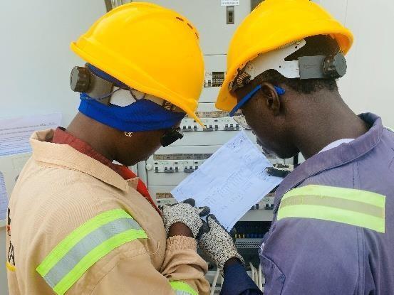 Electrical technicians wearing protective equipment while working on a panel